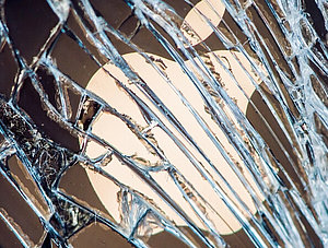 Apple-Logo hinter einer zersplitterten Glasscheibe