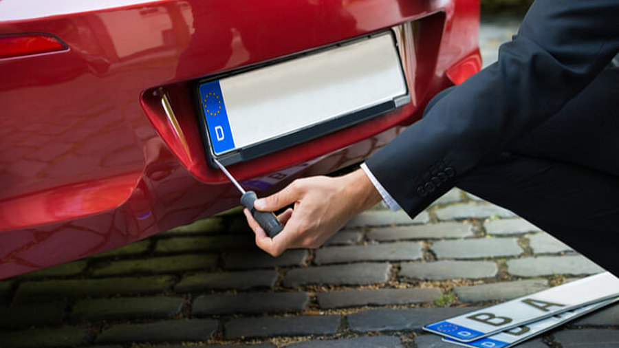 Mann wechselt Auto-Kennzeichen