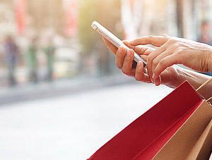 Frau mit Einkaufst&uuml;ten und Smartphone