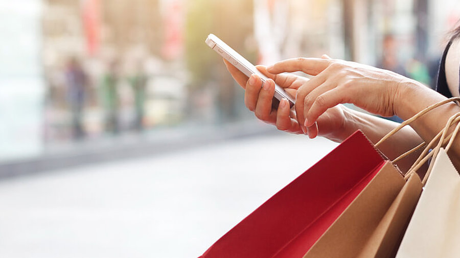 Frau mit Einkaufst&uuml;ten und Smartphone