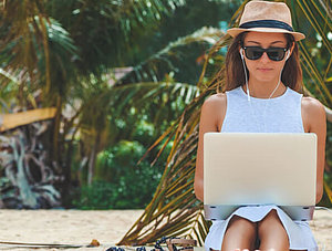 Frau am Strand mit Laptop