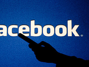 Facebook-Logo mit Schatten einer Frau im Vordergrund