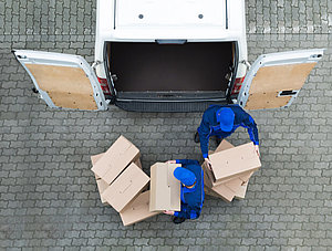 Zwei Paketboten die Pakete aus dem Auto räumen