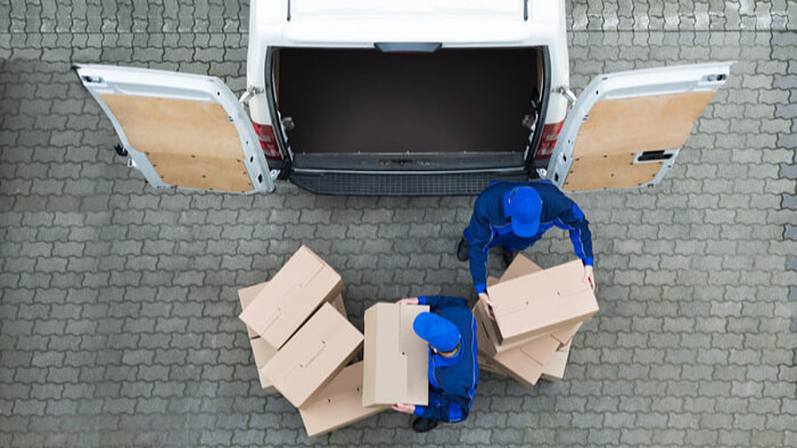 Zwei Paketboten die Pakete aus dem Auto räumen