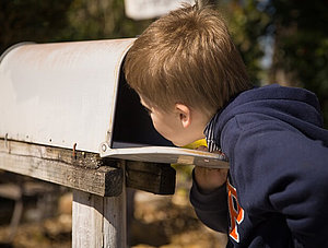 Junge schaut in Briefkasten nach Post