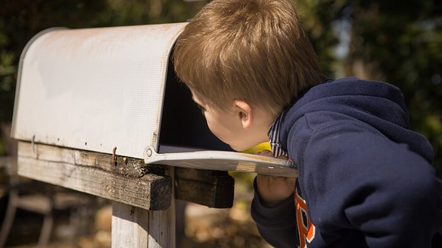 Junge schaut in Briefkasten nach Post