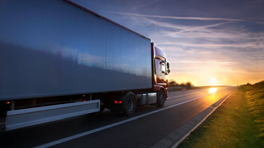 Lkw fährt auf Straße in den Sonnenuntergang