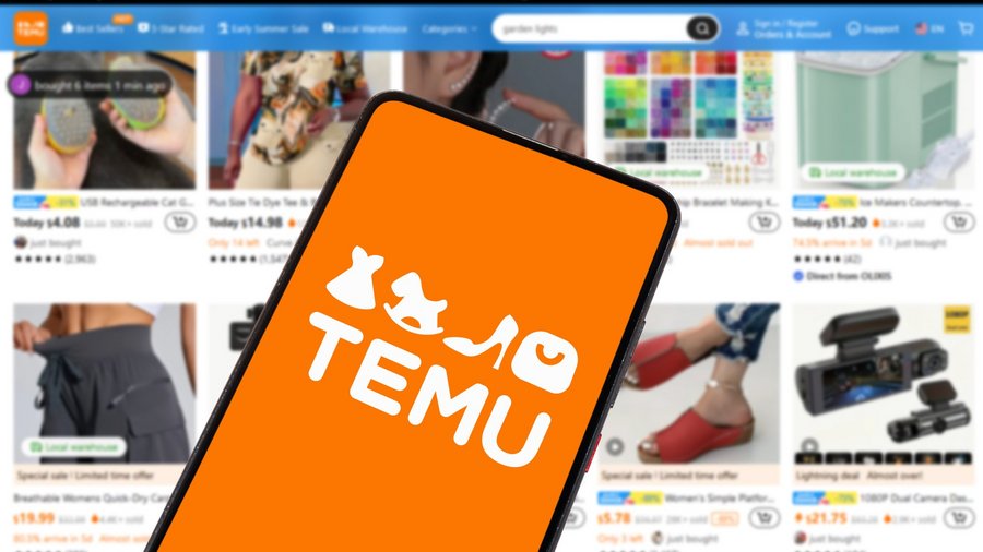 Temu-Logo auf Smartphone welches vor Website-Ansicht gehalten wird.