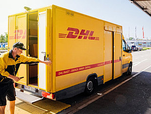 DHL-Zusteller mit Wagen