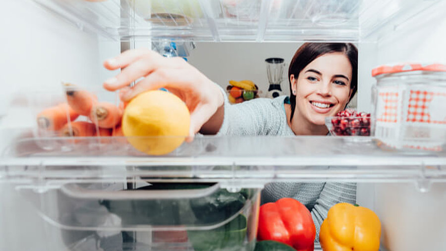 Frau greift in Kühlschrank