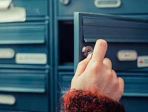 Frau öffnet Briefkasten