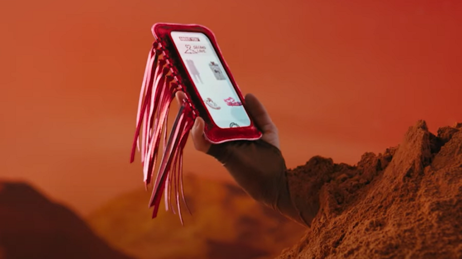 Frau mit rotem Sand bedeckt auf Mars h&auml;lt Smartphone mit About You