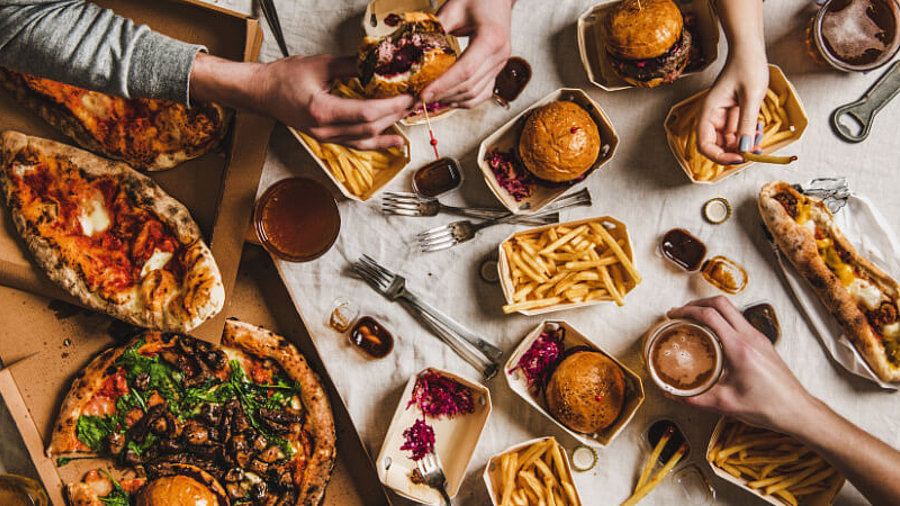 Fastfood-Abendessen vom Lieferdienst: Freunde essen Burger, Pommes und Pizza
