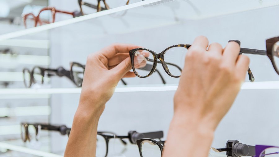 Person nimmt Brille aus Auslage beim Optiker