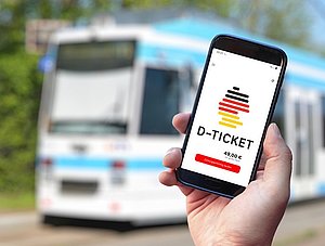 Deutschlandticket auf Smartphone, Tram im Hintergrund