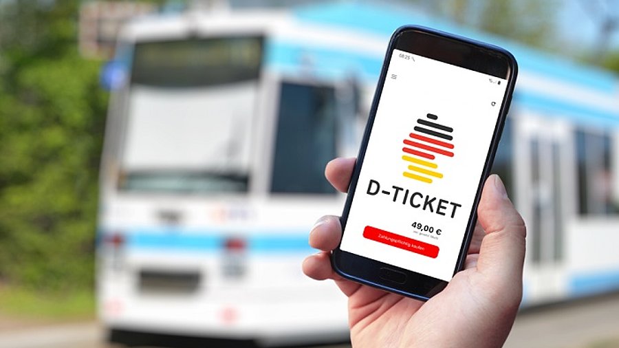 Deutschlandticket auf Smartphone, Tram im Hintergrund