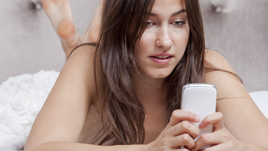 Frau im Bett mit Smartphone