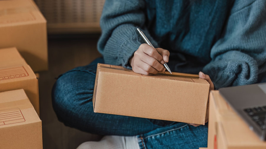 Person schreibt Adresse auf Paket