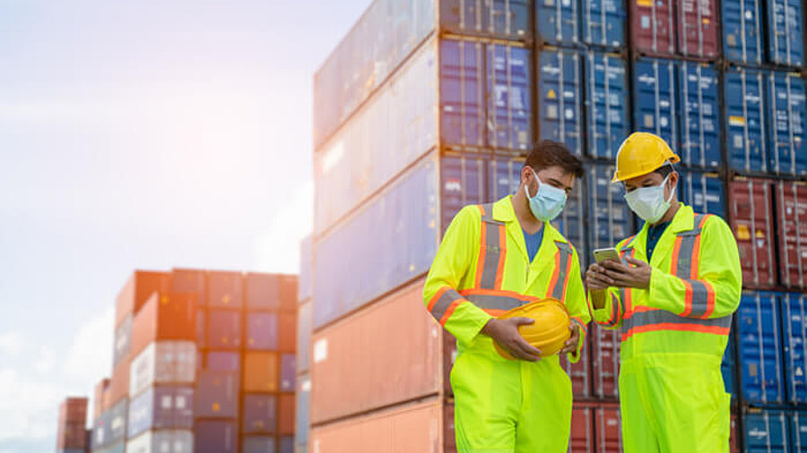 Logistiker mit Maske vor Containern