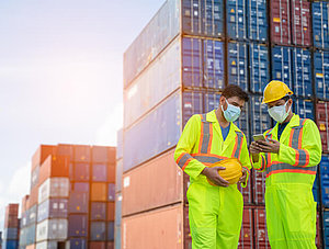 Logistiker mit Maske vor Containern