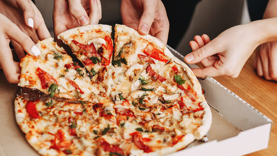 Menschen greifen nach einer Pizza