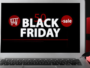 Laptop mit Black Friday Schriftzug umringt von Geschenkpaketen