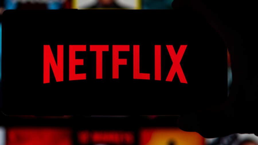 Netflix-Logo auf Smartphone und Homepage im Hintergrund