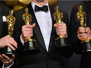 Menschen halten vier Oscars