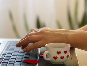 Frau am Laptop mit Herz-Tasse