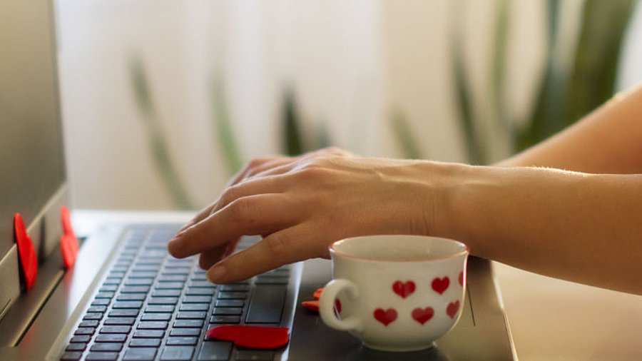 Frau am Laptop mit Herz-Tasse