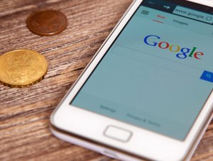 Google auf Smartphone mit Kleingeld