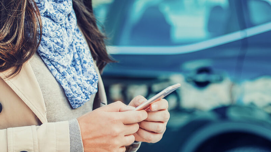 Frau mit Smartphone und Auto