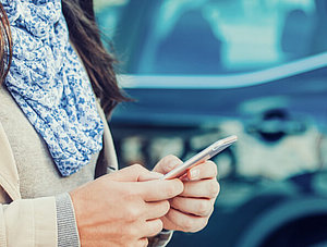 Frau mit Smartphone und Auto