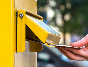 Einen Brief in einen deutschen gelben Briefkasten werfen