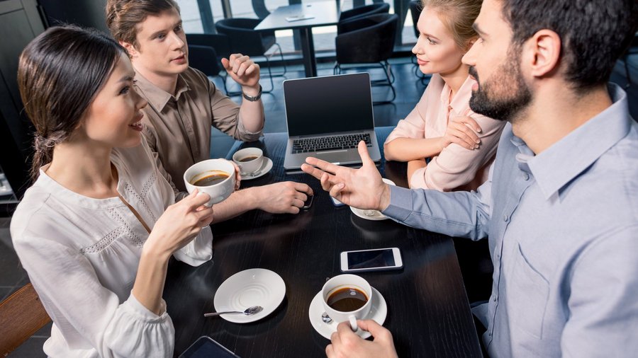 Mitarbeitende sitzen mit Kaffeetassen im Pausenraum