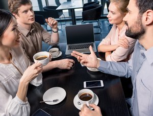 Mitarbeitende sitzen mit Kaffeetassen im Pausenraum