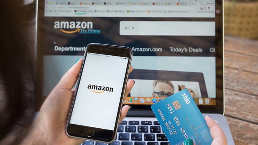 Smartphone, Kreditkarte und Laptop mit Amazon