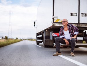 Älterer Lkw Fahrer sitzt neben seinem LKW