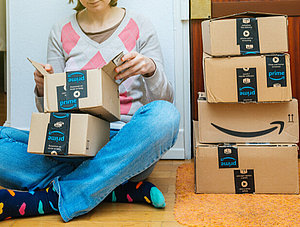 Frau sitzt mit Amazon Paketen aufm Boden