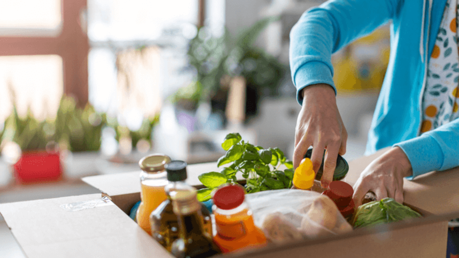 Frau nimmt Lebensmittel aus Paket