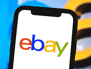 Ebay auf Smartphone vor Ebay-Schriftzug