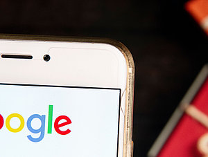 Google-Logo auf Smartphone, Weihnachtsgeschenke im Hintergrund