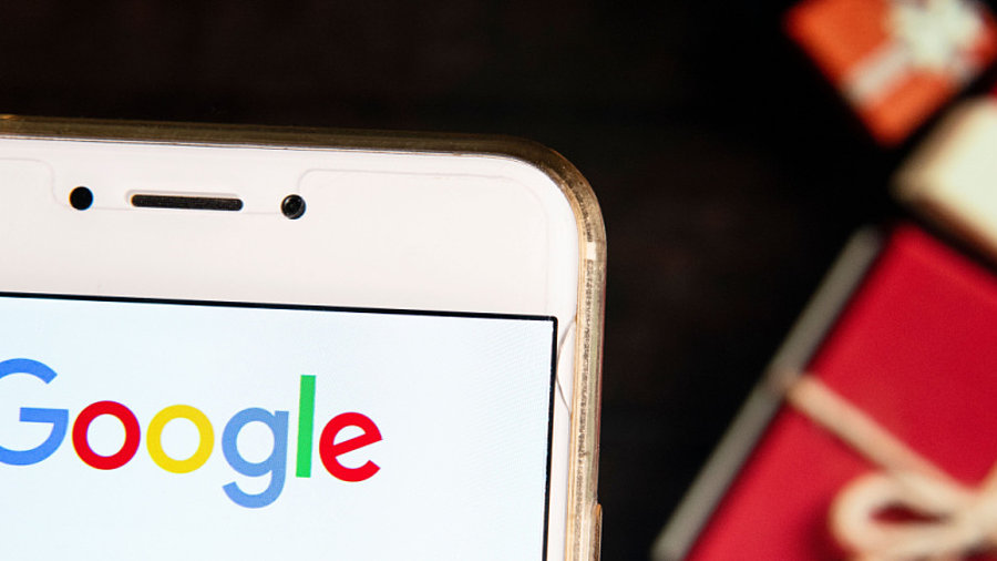 Google-Logo auf Smartphone, Weihnachtsgeschenke im Hintergrund