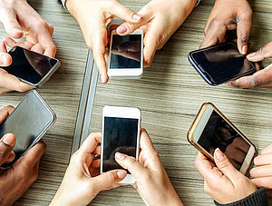 Gruppe von Freunden, die sich gemeinsam mit Smartphones am&uuml;sieren