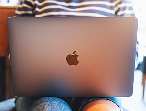 Frau mit Apple-Laptop auf dem Schoß