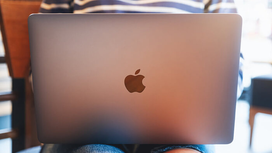 Frau mit Apple-Laptop auf dem Schoß