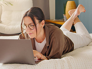 Frau auf Bett mit Laptop