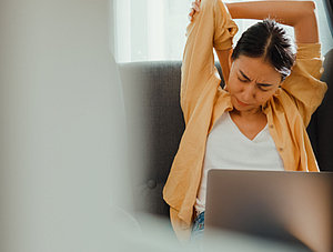 Frau k&auml;mpft mit Belastung bei der Arbeit am Laptop