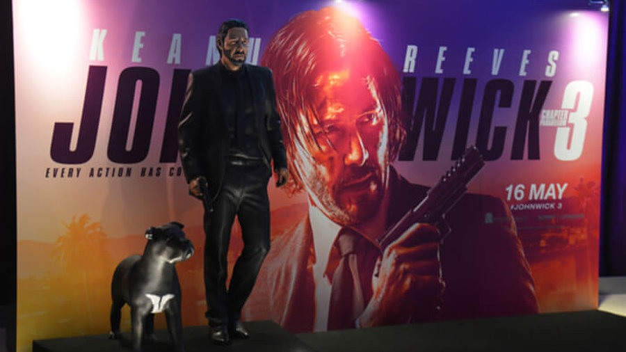 Abbild von Keanu Reeves vor einem Filmplakat von John Wick: Kapitel 3