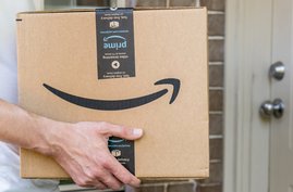 Mann hält Amazon-Paket vor Haustür